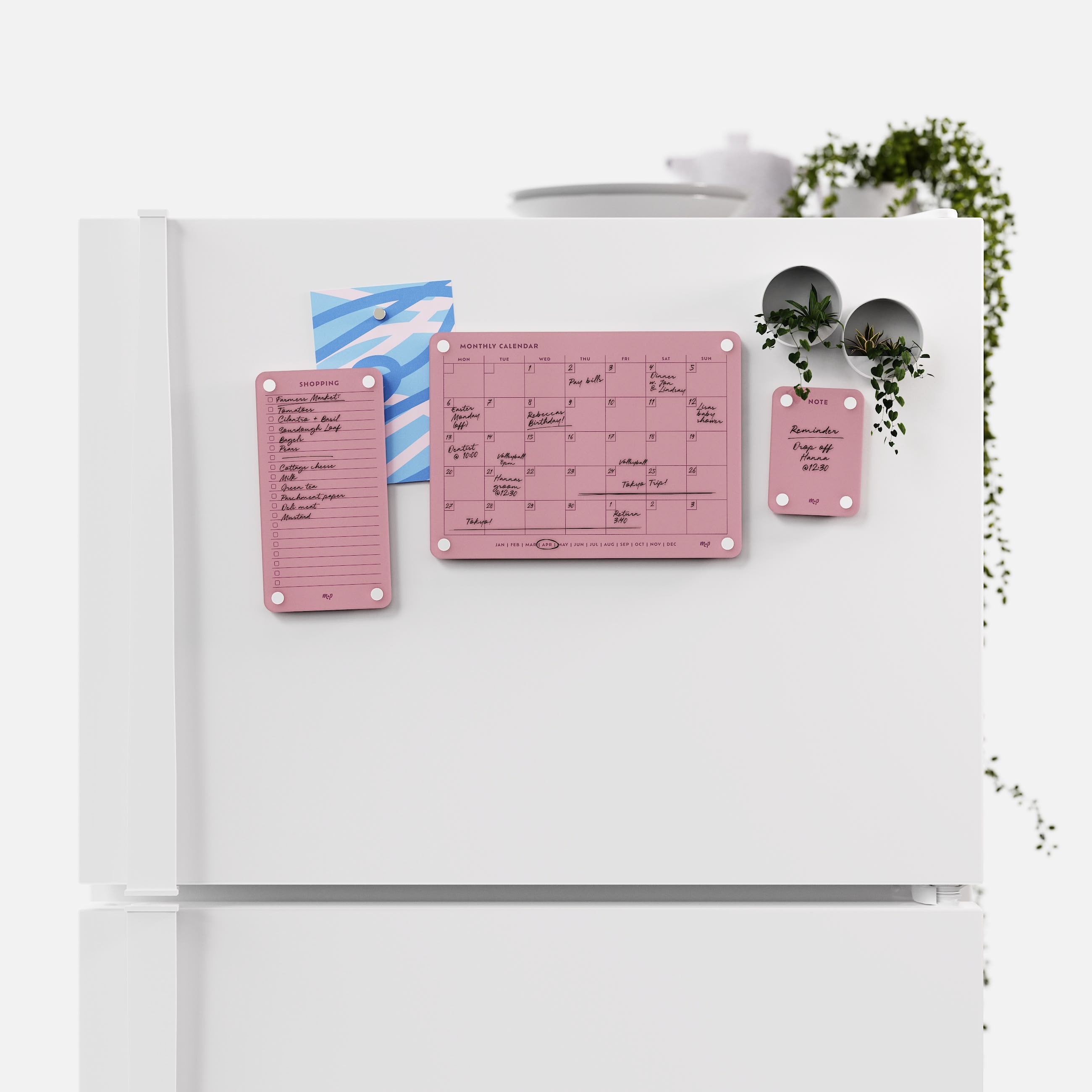 Plum shopping list, monthly calendar and note board arranged across a white fridge door